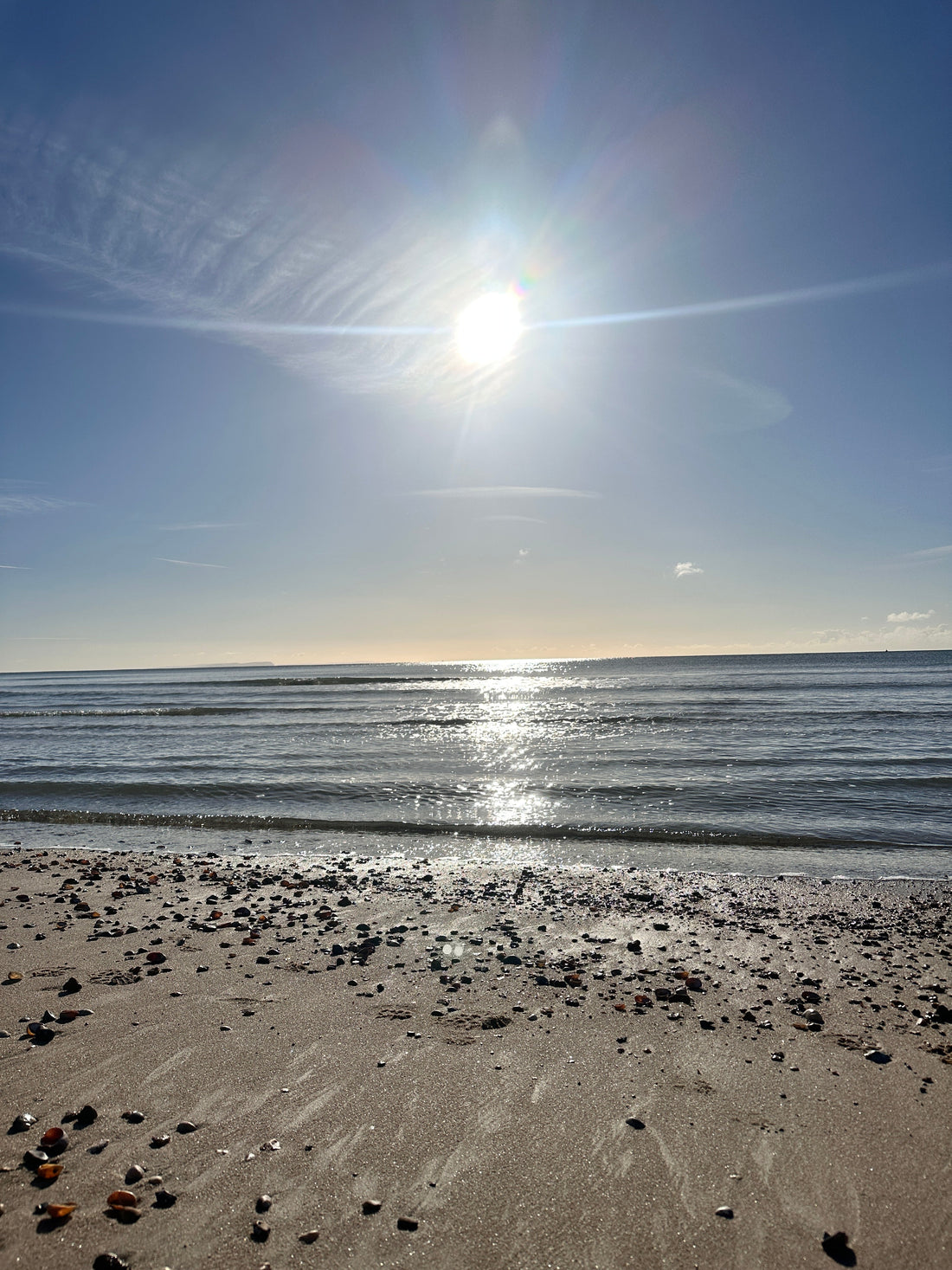 Dorset artist Kate Shephard filming the sea on a calm sunny morning, sun sparkling on still water on the Dorset coast.